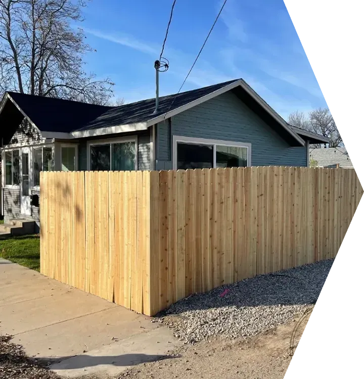 New wooden privacy fence around a blue house beside a driveway