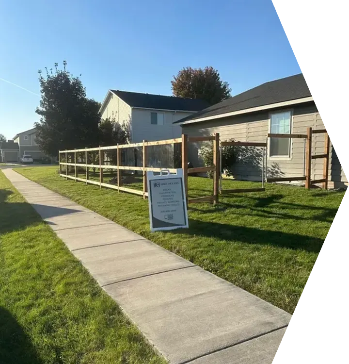 Residential sidewalk beside a grassy yard with a wooden railing and a sign near houses in bright sunlight Residential sidewalk beside a grassy yard with a wooden railing and a sign near houses in bright sunlight
