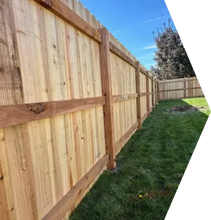Wooden privacy fence along a grassy backyard, viewed in perspective under a clear sky Wooden privacy fence along a grassy backyard, viewed in perspective under a clear sky