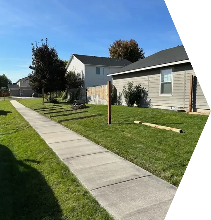 Suburban sidewalk beside a green lawn and beige houses under a bright blue sky Suburban sidewalk beside a green lawn and beige houses under a bright blue sky