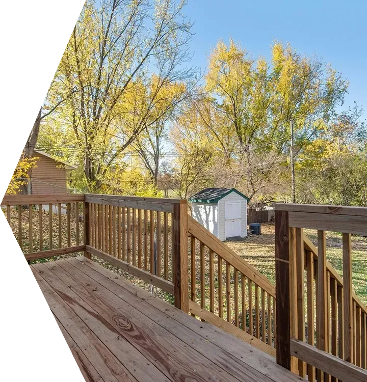 Wooden deck with railings overlooking a sunny autumn backyard with yellow trees and a small shed. Wooden deck with railings overlooking a sunny autumn backyard with yellow trees and a small shed.
