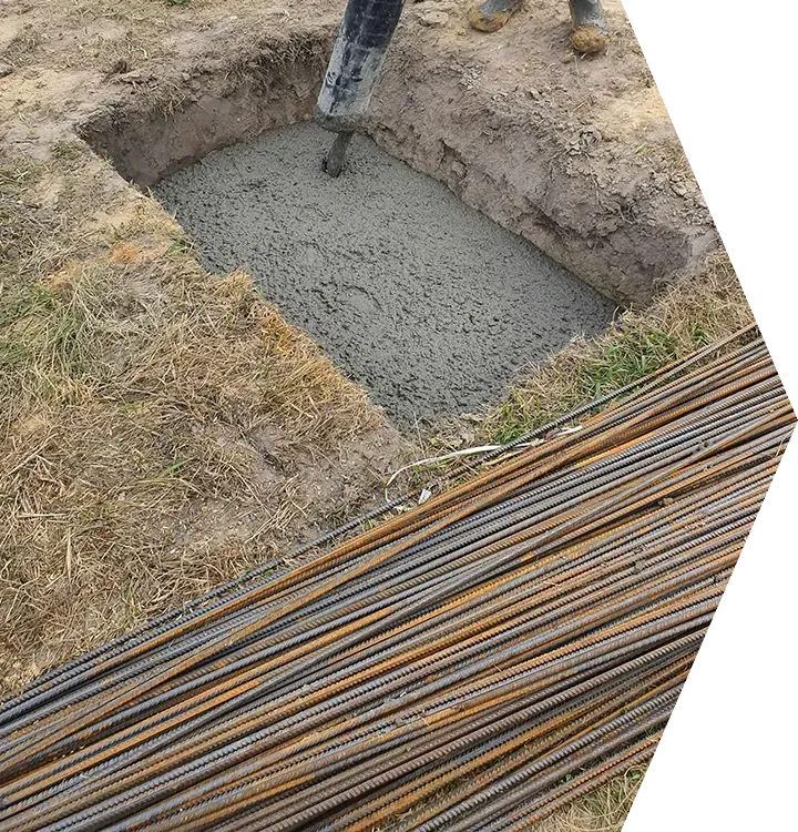 Concrete poured into a dug foundation pit beside stacked steel rebar at a construction site Concrete poured into a dug foundation pit beside stacked steel rebar at a construction site
