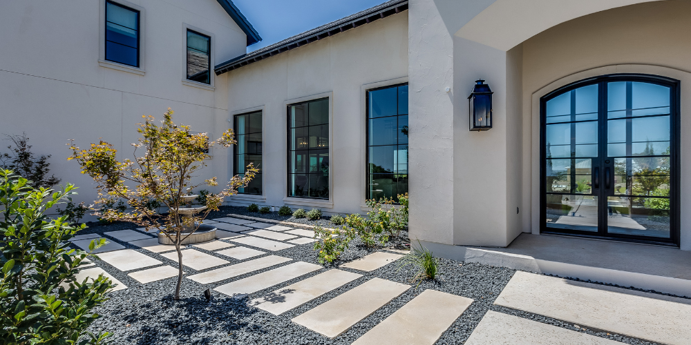 A white house with black windows and a walkway in front of it.