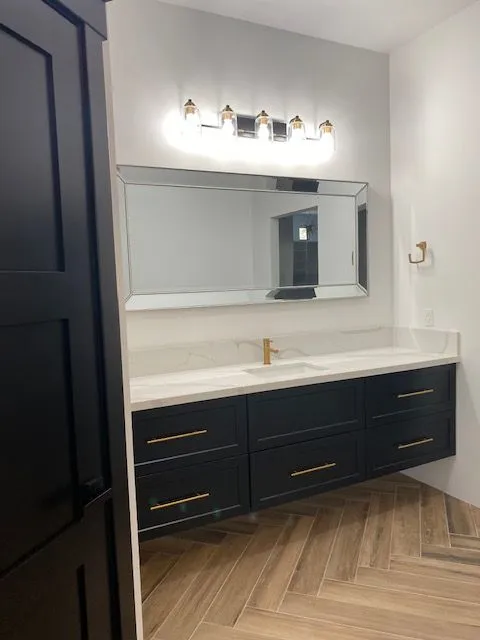 A bathroom with black cabinets and a large mirror