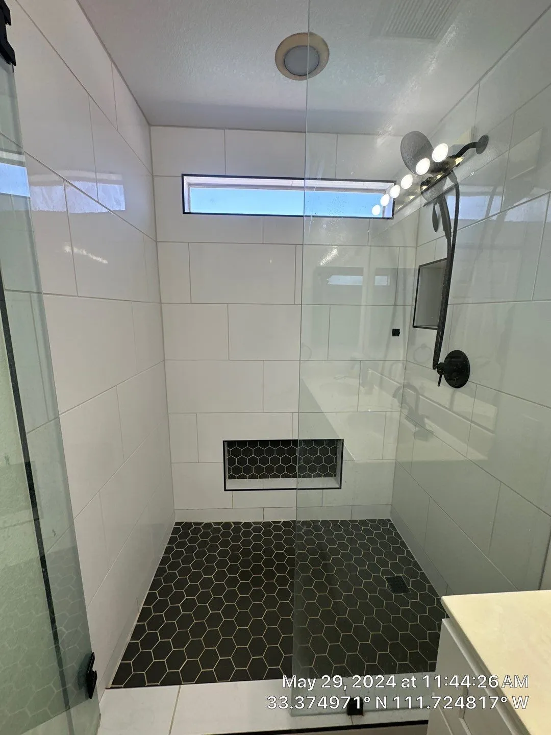 A bathroom with a walk in shower and a window.