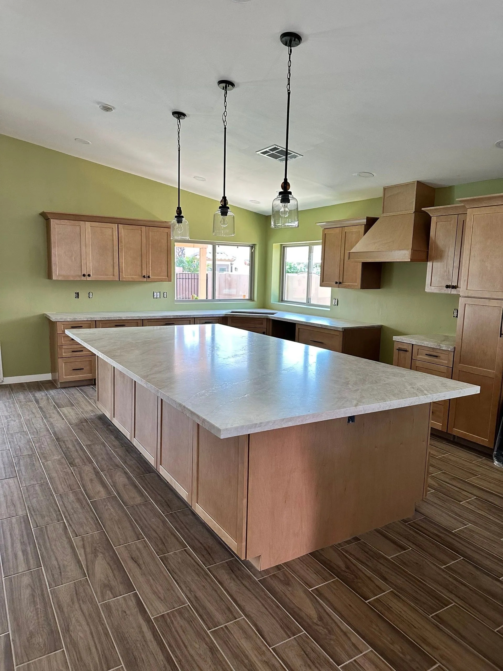A kitchen with wooden cabinets and a large island in the middle.
