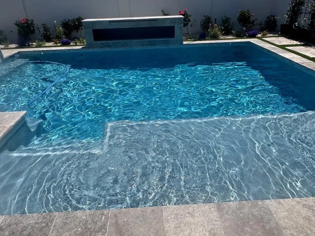 A large swimming pool with a waterfall in the backyard.