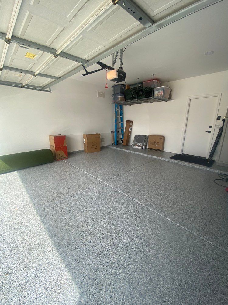 A garage with a garage door open and boxes on the floor.