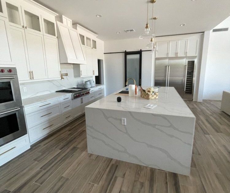 A kitchen with white cabinets and a large island in the middle.