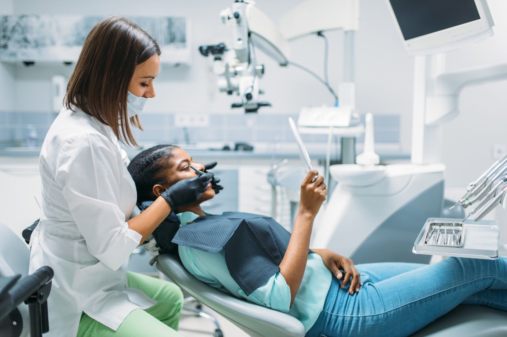 A female dentist is examining a patient 's teeth in a dental office.