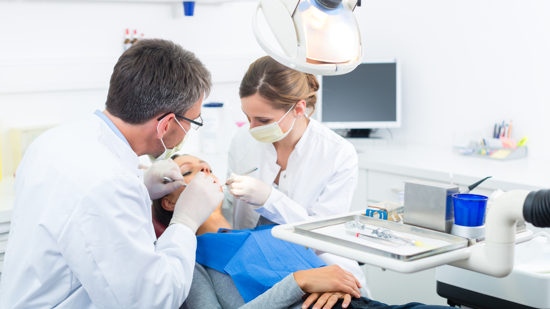 A dentist is examining a patient 's teeth in a dental office.