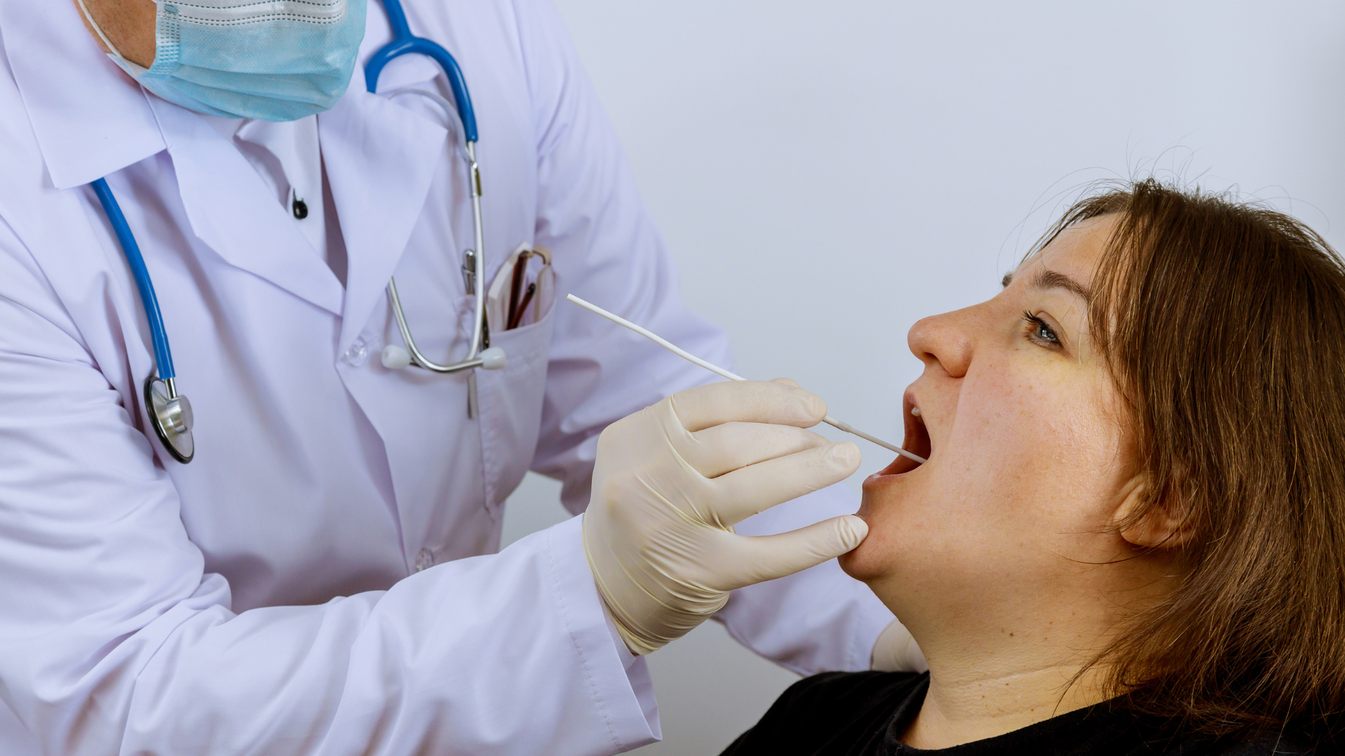 A woman is sitting in a dental chair looking at her teeth in a mirror.