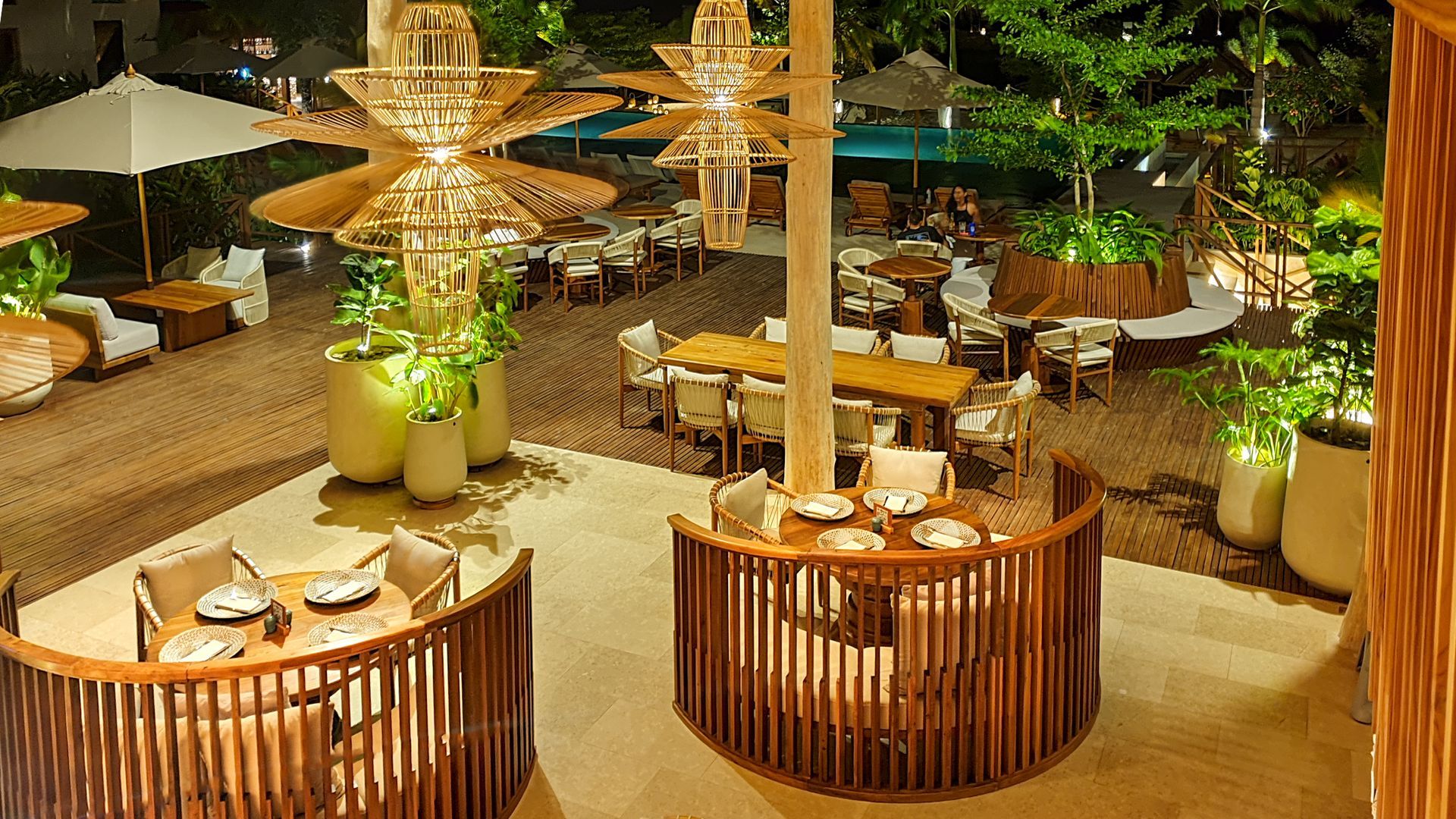 Hotel in San Antero with an illuminated restaurant, set tables, greenery, and wood details.