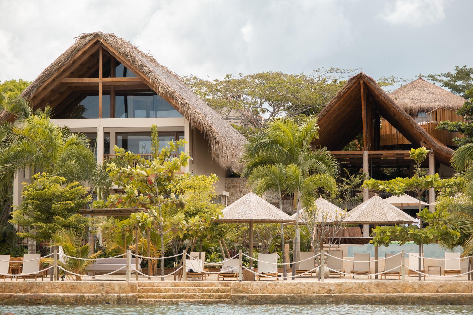 Beachfront hotel in Punta Bolívar, San Antero, with palm cabins, umbrellas, and palm trees.
