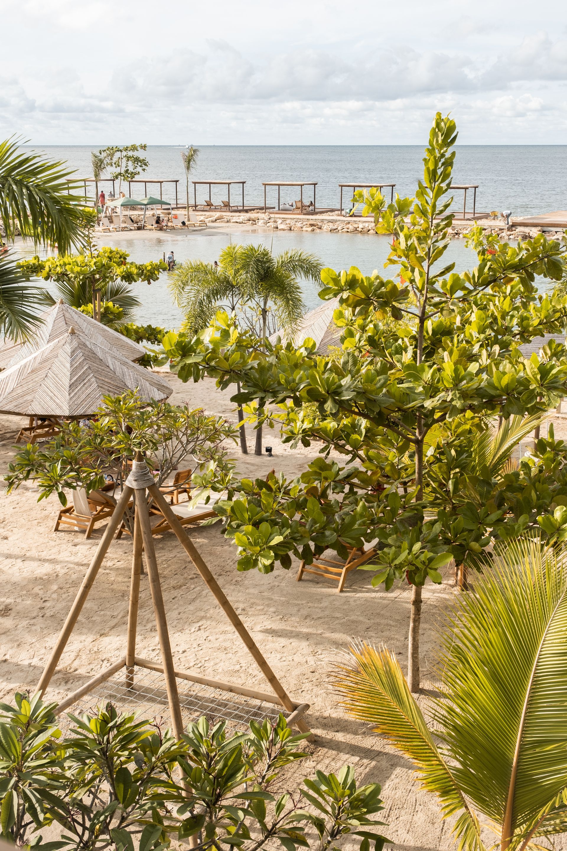 Beachfront hotel in San Antero with pool, palm trees, umbrellas, relaxing spaces, and sea views.