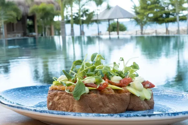 tostada con vegetales y brotes en plato azul servido en Aimarawa, un hotel frente al mar con restaurante en san antero
