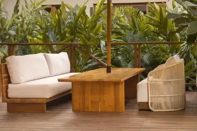 Terraza lounge del Hotel Aimarawa con sofás acolchados, mesa de madera y sillas artesanales, rodeado a naturaleza.