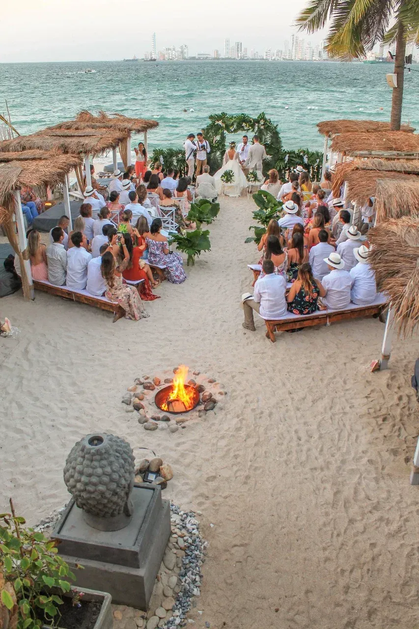 Ceremonia de matrimonio en la playa con arco de flores y fondo del mar en el Hotel Aimarawa de San Antero.