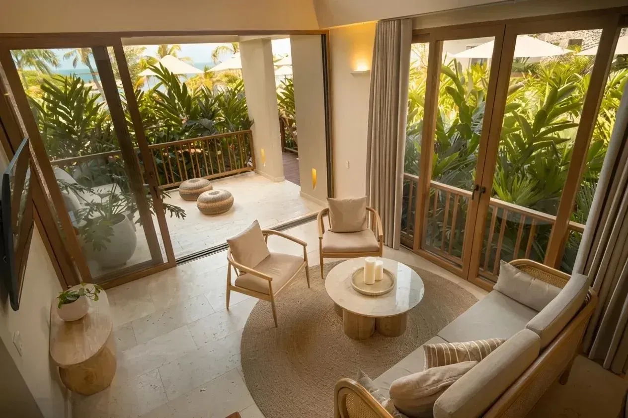 Sala de Aimarawa, hotel en San Antero, con balcón, ventanales y vista a jardines tropicales.