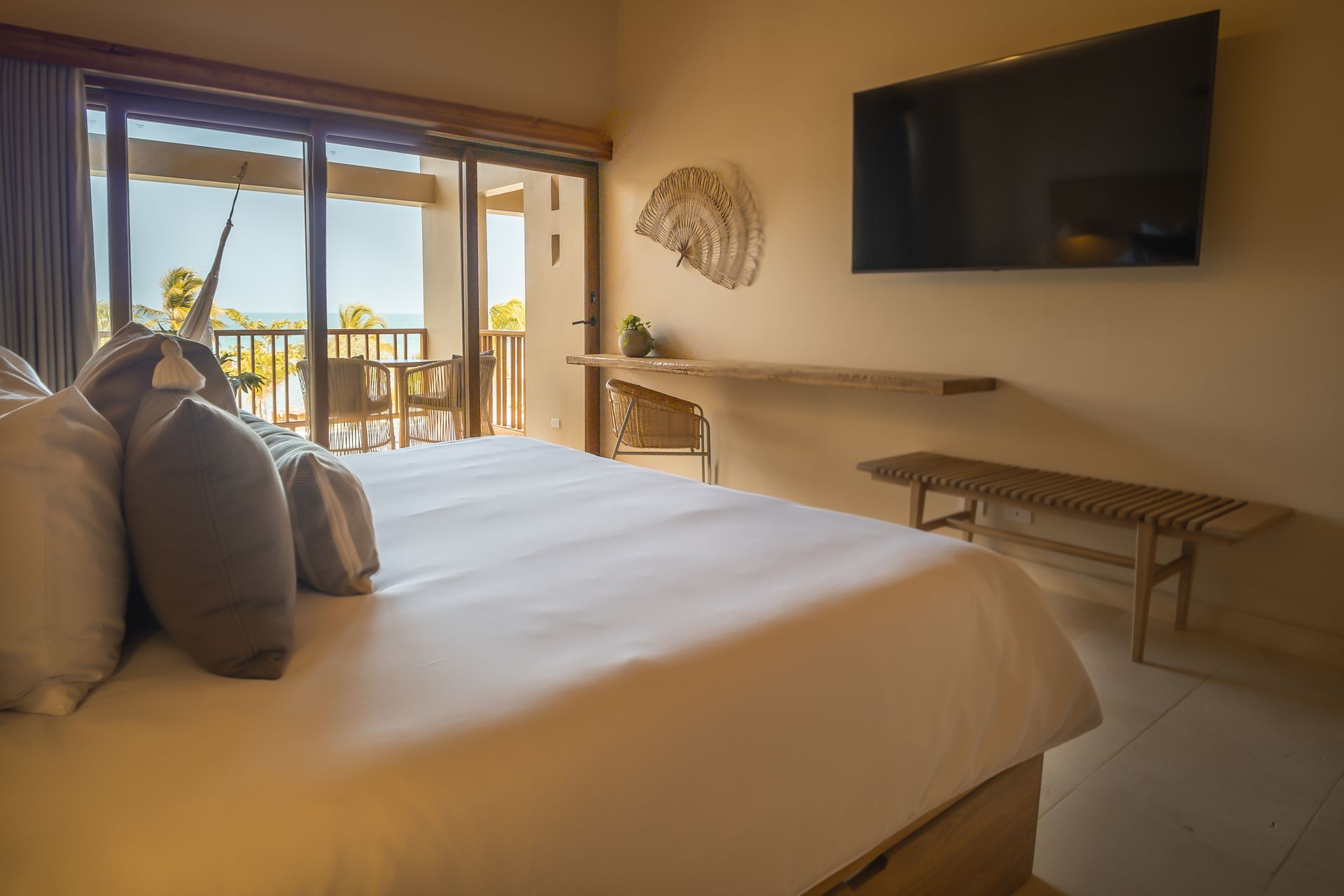 Beachfront hotel in San Antero with a spacious bed, large window, wooden balcony, and natural light.