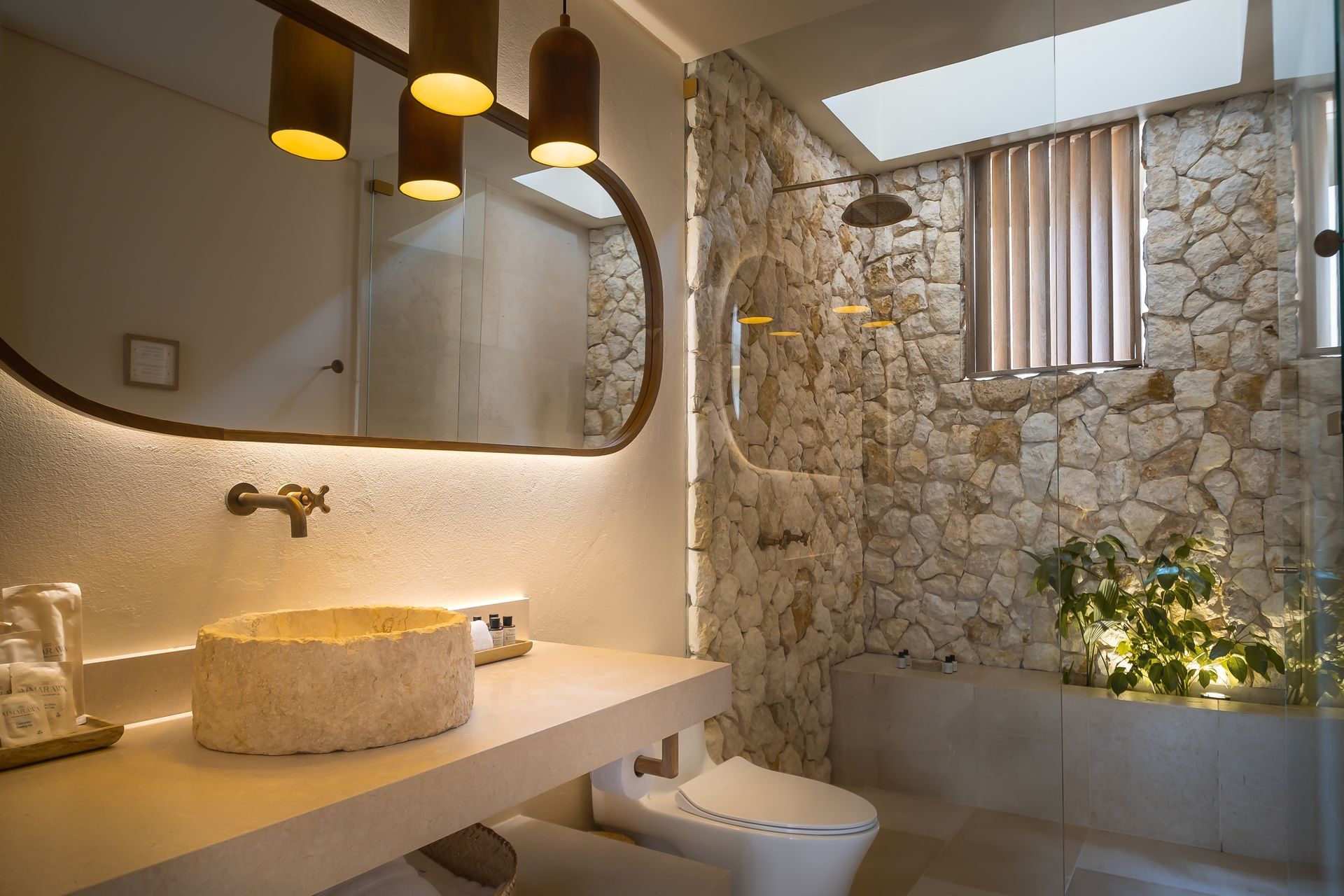 Cabins in San Antero, Córdoba with a stone bathroom, natural sink, organic mirror, and warm lighting.