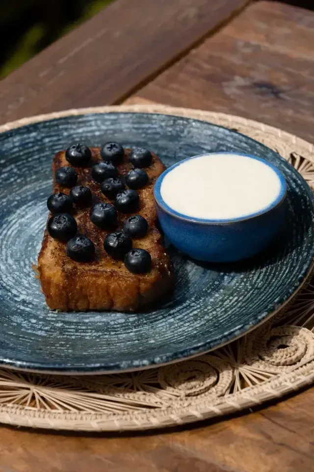 Postre artesanal de pan caramelizado con arándanos frescos y crema, servido en Guadua restaurante del Hotel Aimarawa