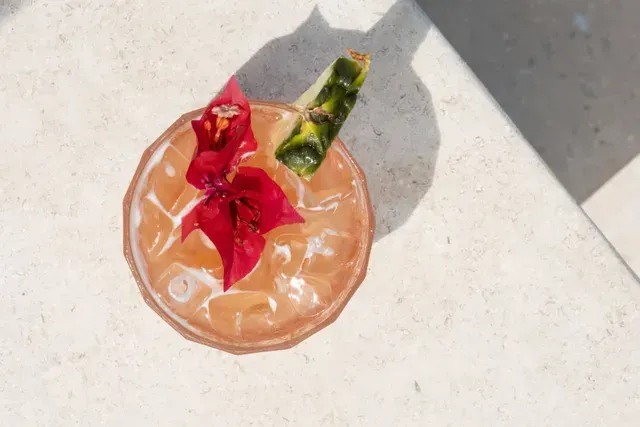 cóctel con hielo, flor roja y piña sobre superficie clara en hotel en san antero frente a la playa