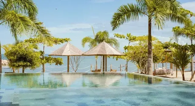 Aimarawa pool, hotel in San Antero, with palm trees, umbrellas, hammocks, and ocean views.