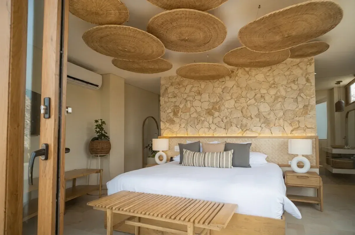 Habitación de hotel en san antero córdoba con cama amplia, techo en decorado, muro en piedra y una atmósfera serena.