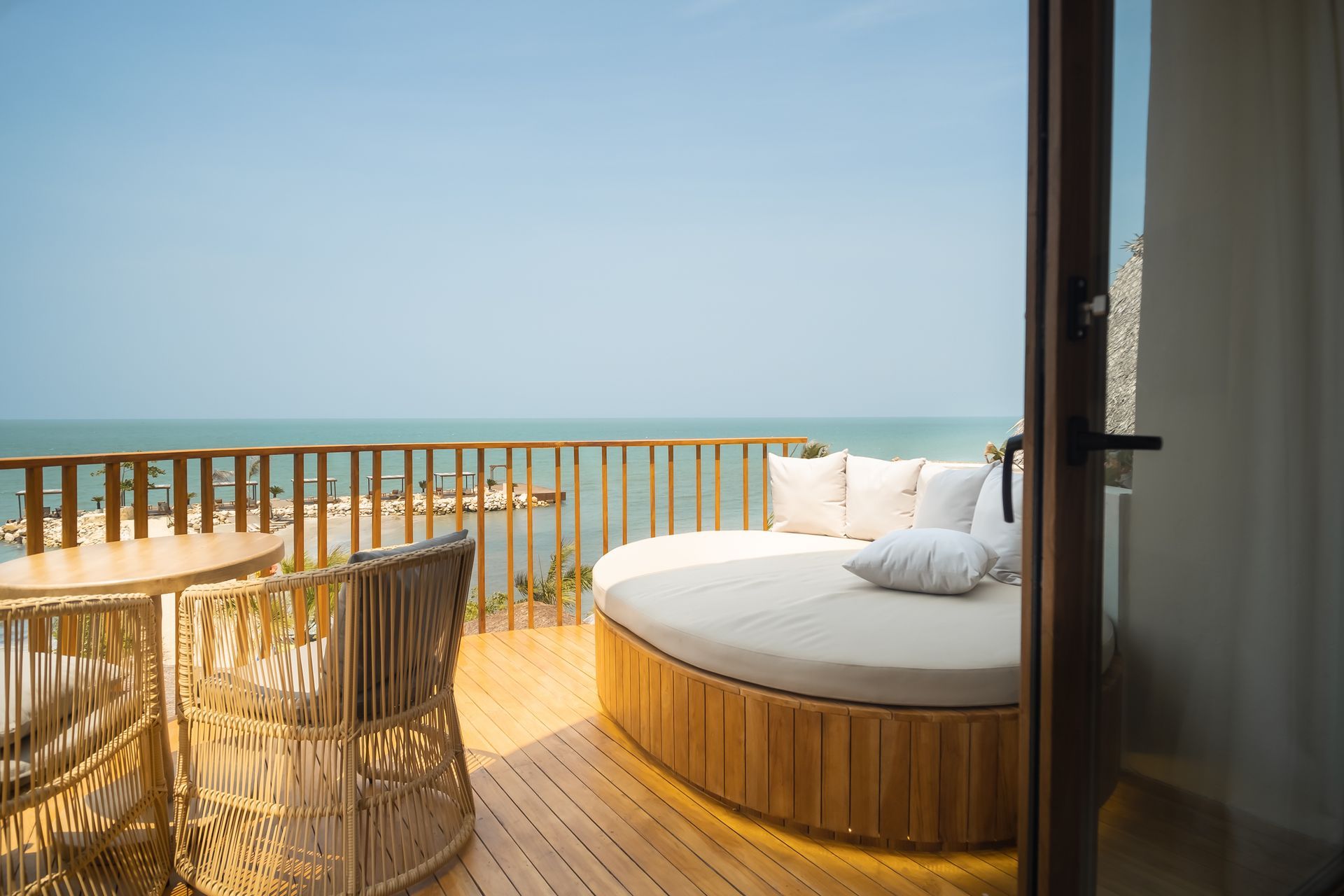 Oceanfront lodging in San Antero with a terrace, large round sofa, wooden railing, and dining table.