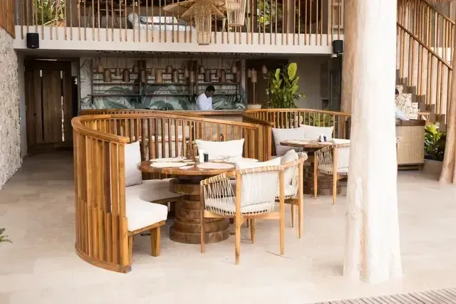 Restaurante del Hotel Aimarawa en San Antero con mesas circulares de madera, sillas claras y bar al fondo.