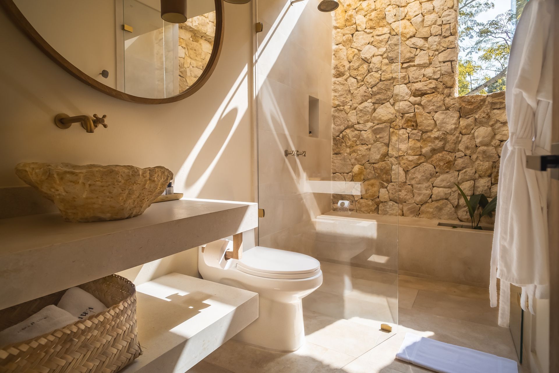 Accommodation in San Antero, Colombia, with shower, stone sink, round mirror, and natural light.