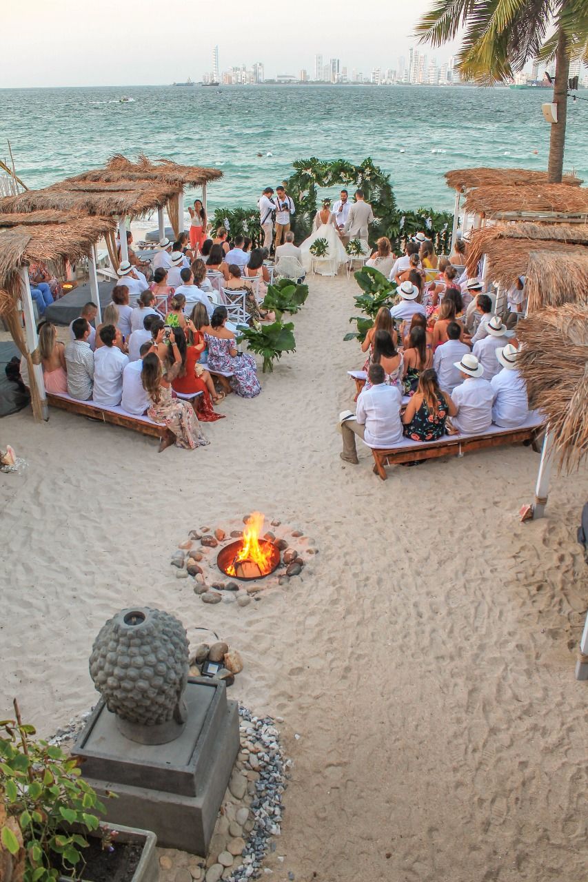Beach wedding ceremony with a floral arch and ocean background at Hotel Aimarawa in San Antero Colombia