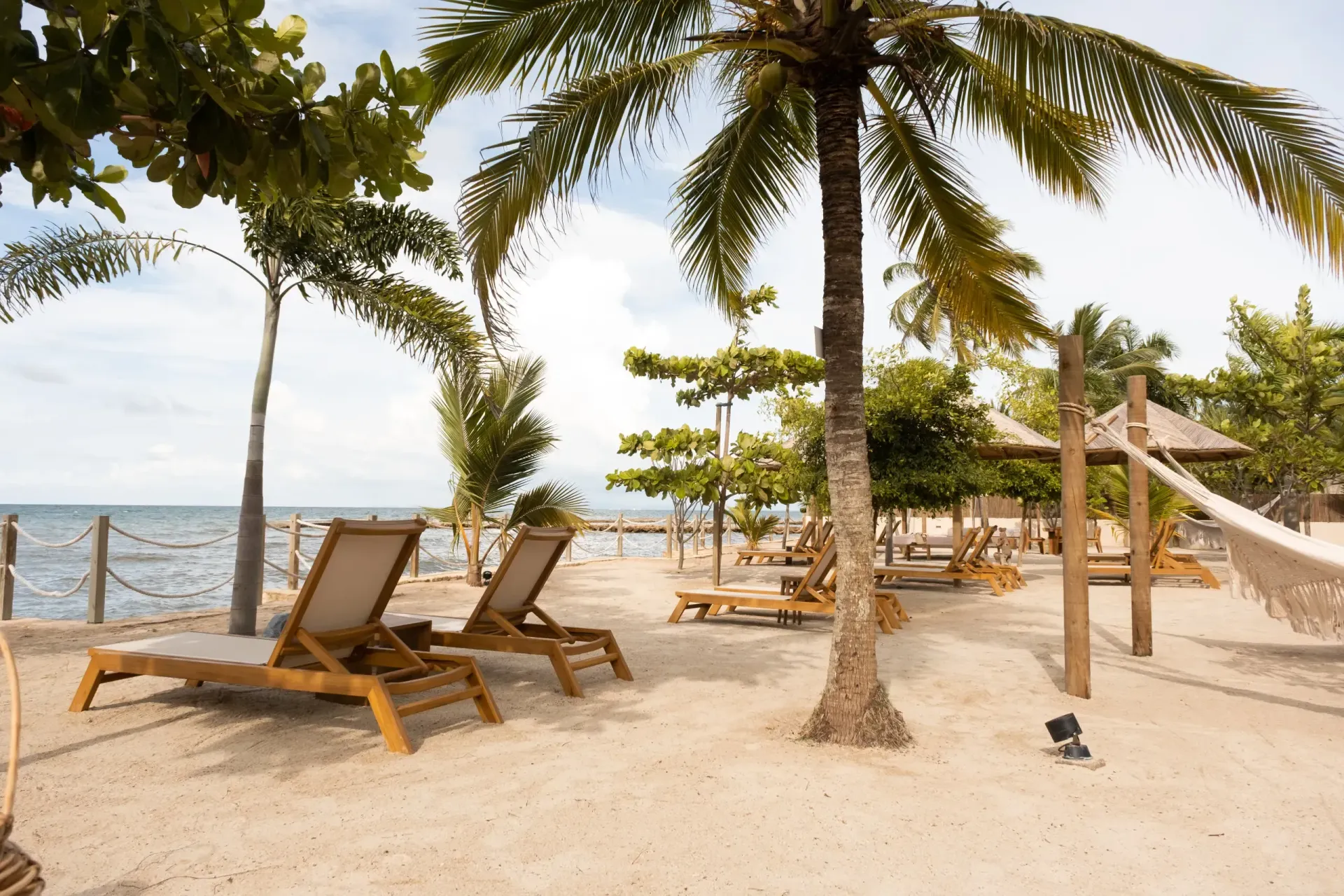 Aimarawa, beachfront hotel in San Antero, with beach chairs, palm trees, sand, and Caribbean Sea views.