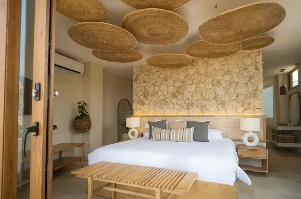 Habitación de hotel en san antero córdoba con cama amplia, techo en decorado, muro en piedra y una atmósfera serena.