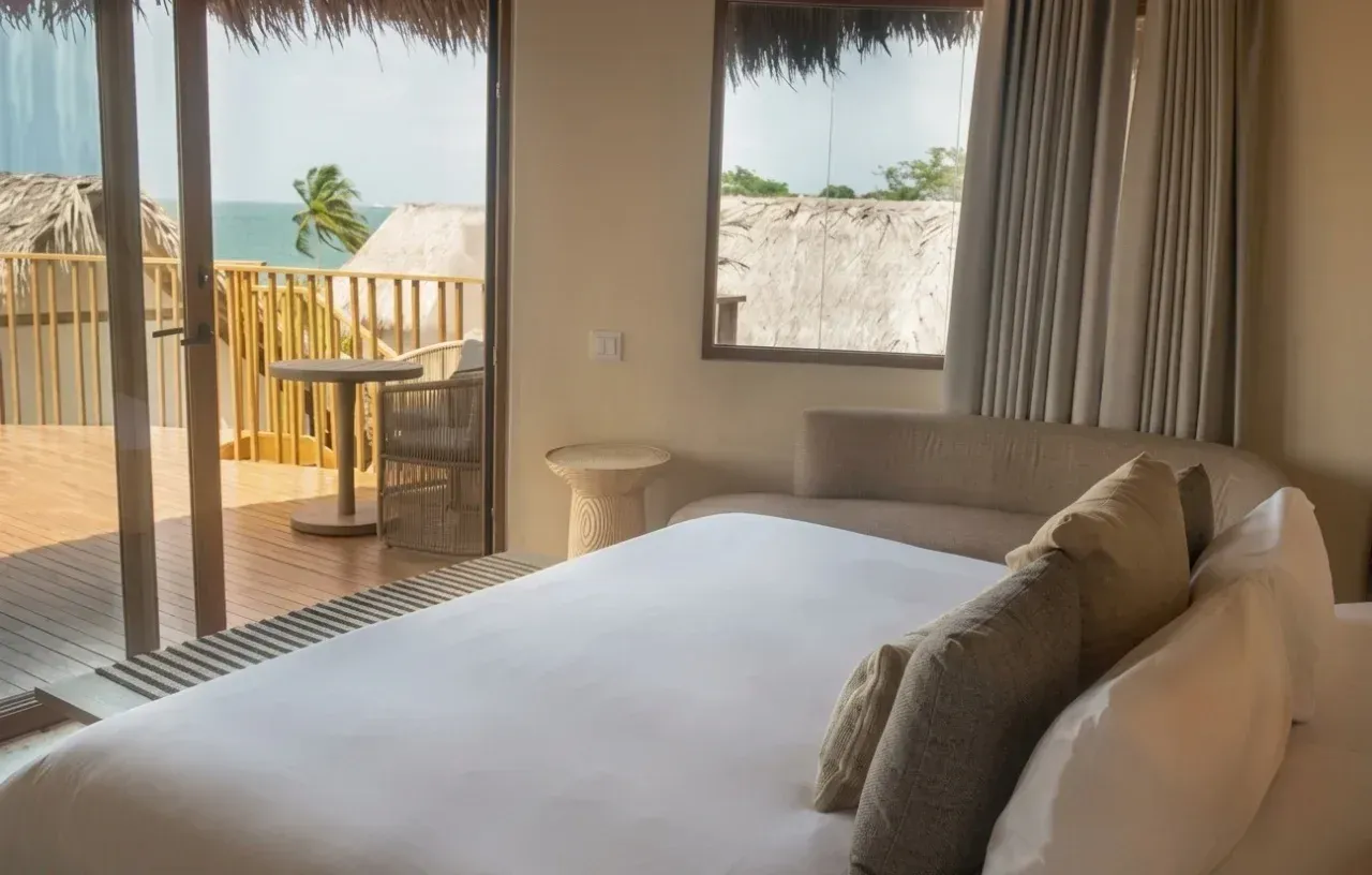 cabañas en san antero cordoba con cama amplia, ventanal, balcón con baranda de madera y luz natural.