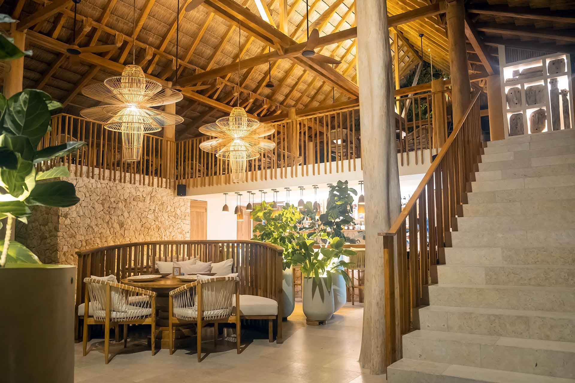 restaurantes en san antero cordoba del Hotel Aimarawa con techo de palma, mesas de madera, escalera y luz cálida.