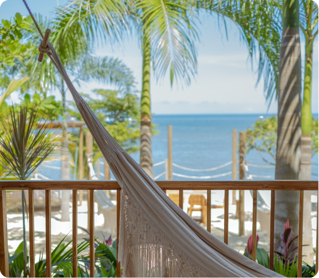 Hammock facing the sea at a hotel in San Antero, with palm trees, wooden railing, and water views.