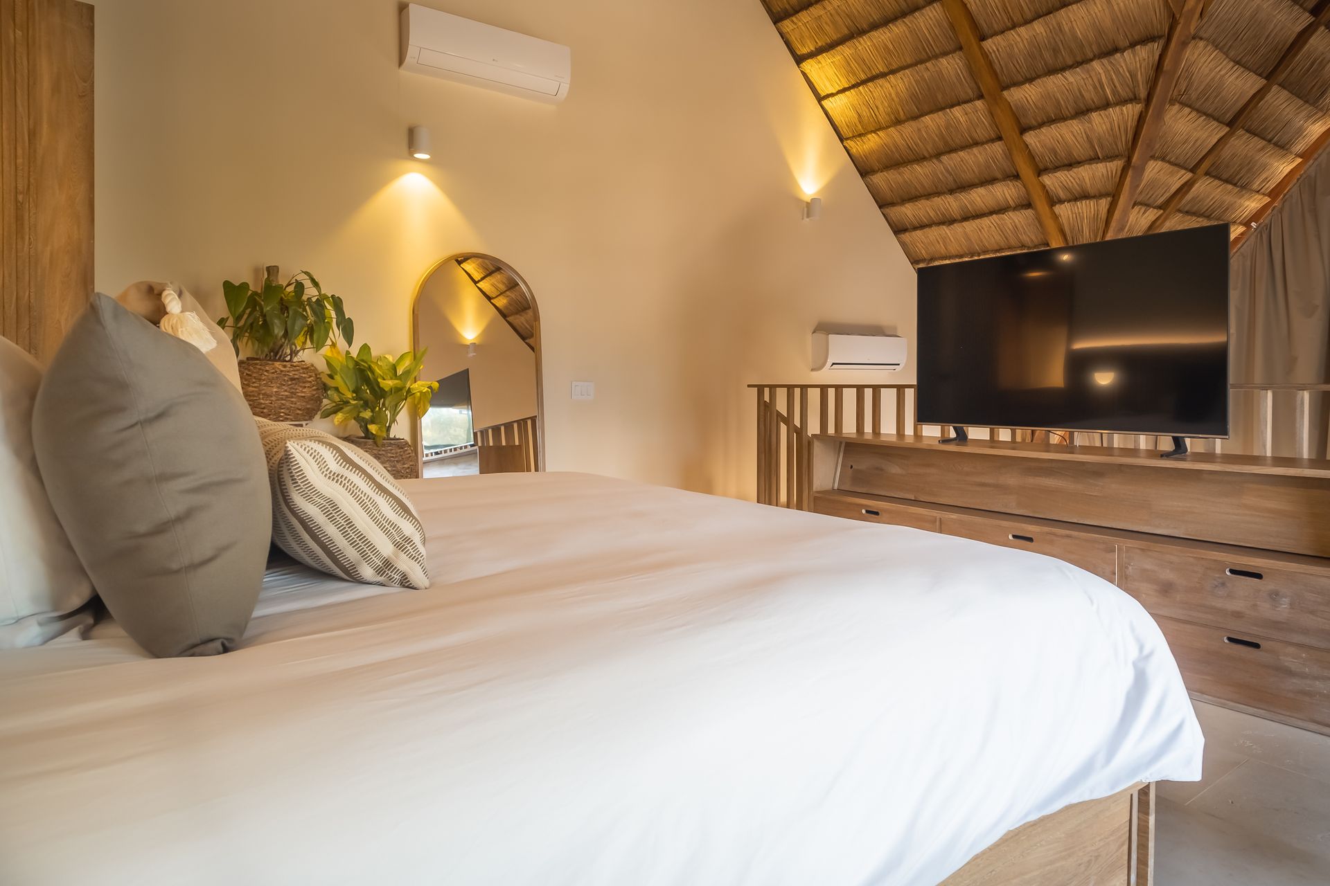 Accommodation in San Antero with a spacious bed, palm roof, natural wood, and TV.