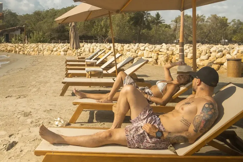 pareja acostada en sillas de playa, disfrutando de las playas de san antero frente a hotel aimarawa