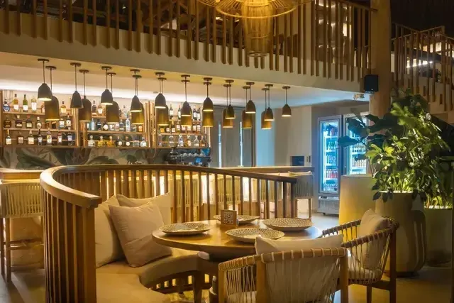 Bar y restaurante del Hotel Aimarawa en San Antero con barra iluminada, sillas altas y mesas servidas.