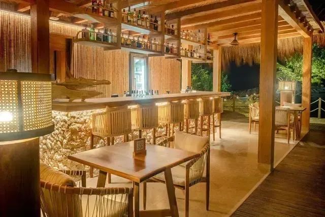 Bar Ara Macao en Hotel Aimarawa en San Antero con barra en madera, sillas altas y ambiente cálido tropical.