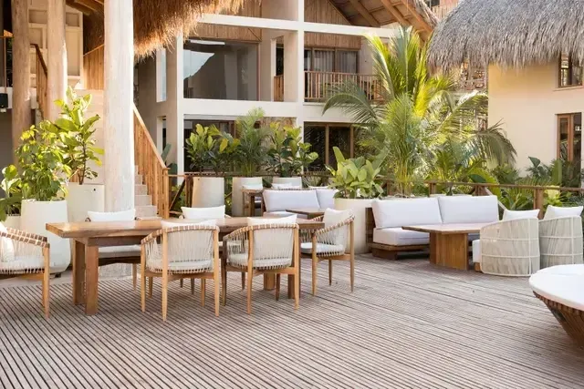 Restaurant at Hotel Aimarawa in San Antero, Colombia, with wooden tables, light chairs, and tropical greenery.