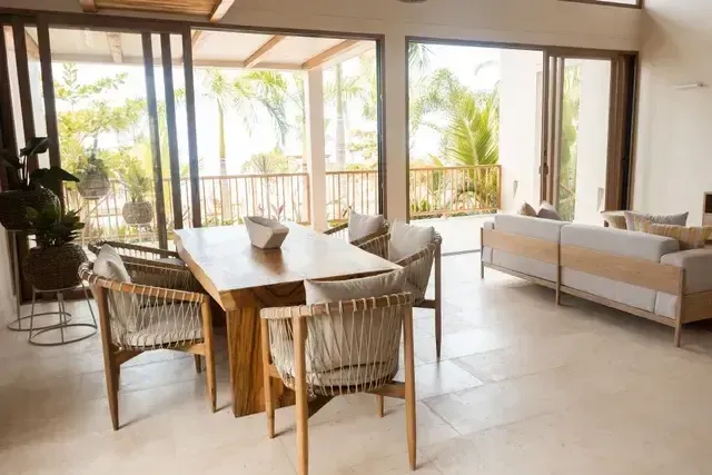 Sala comedor del Hotel Aimarawa San Antero con mobiliario en madera, sillas artesanales y ventanales con vista a al jardín