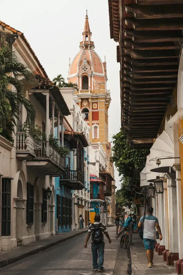 Torre de iglesia colonial vista entre fachadas y balcones en el centro histórico.