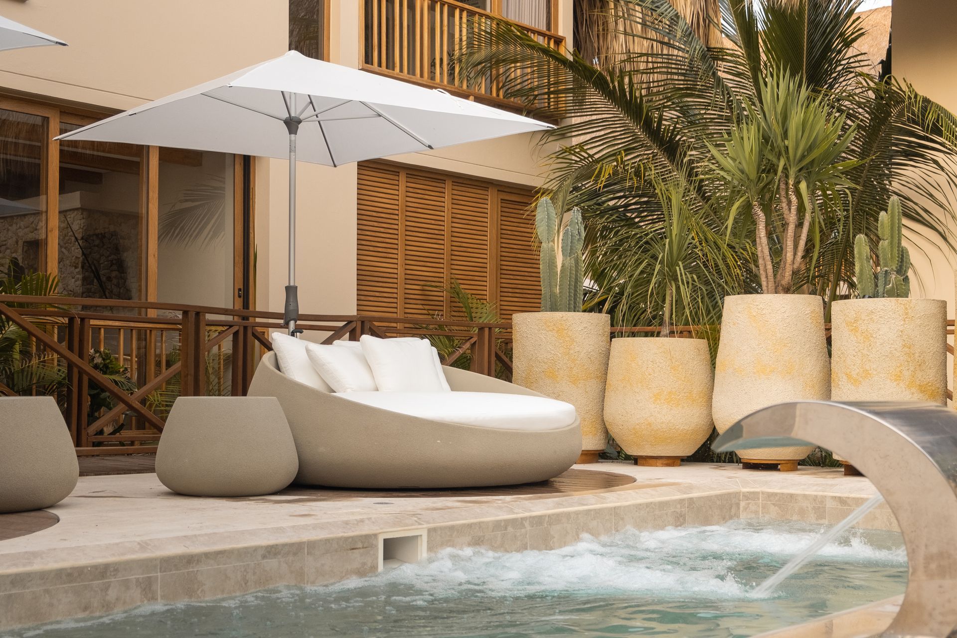 Aimarawa, hotel with pool in San Antero, with white loungers, umbrella, palm trees, cacti, and thatched roof.