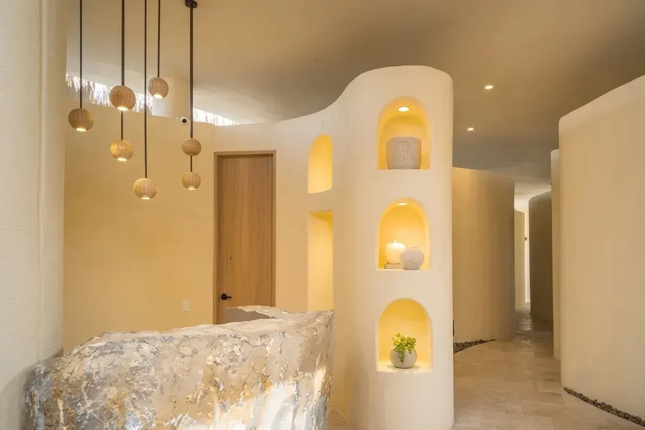 Aimarawa hotel en san antero con spa, recepción en piedra, paredes curvas y estantes iluminados.