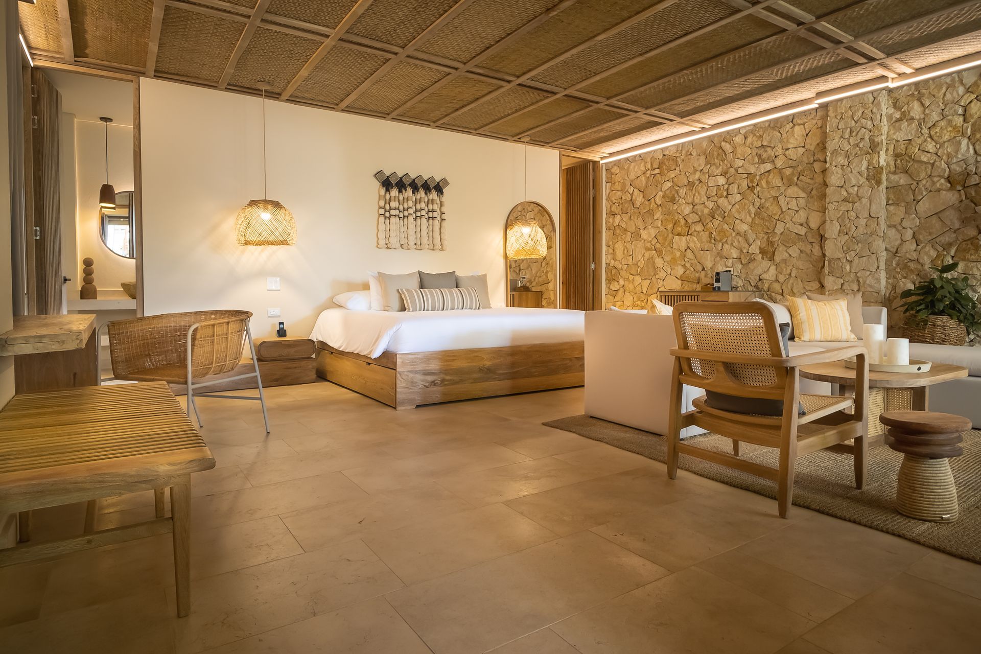 Hotels in San Antero, Colombia, with a king suite, sofa, wooden table, woven ceiling, and stone wall.
