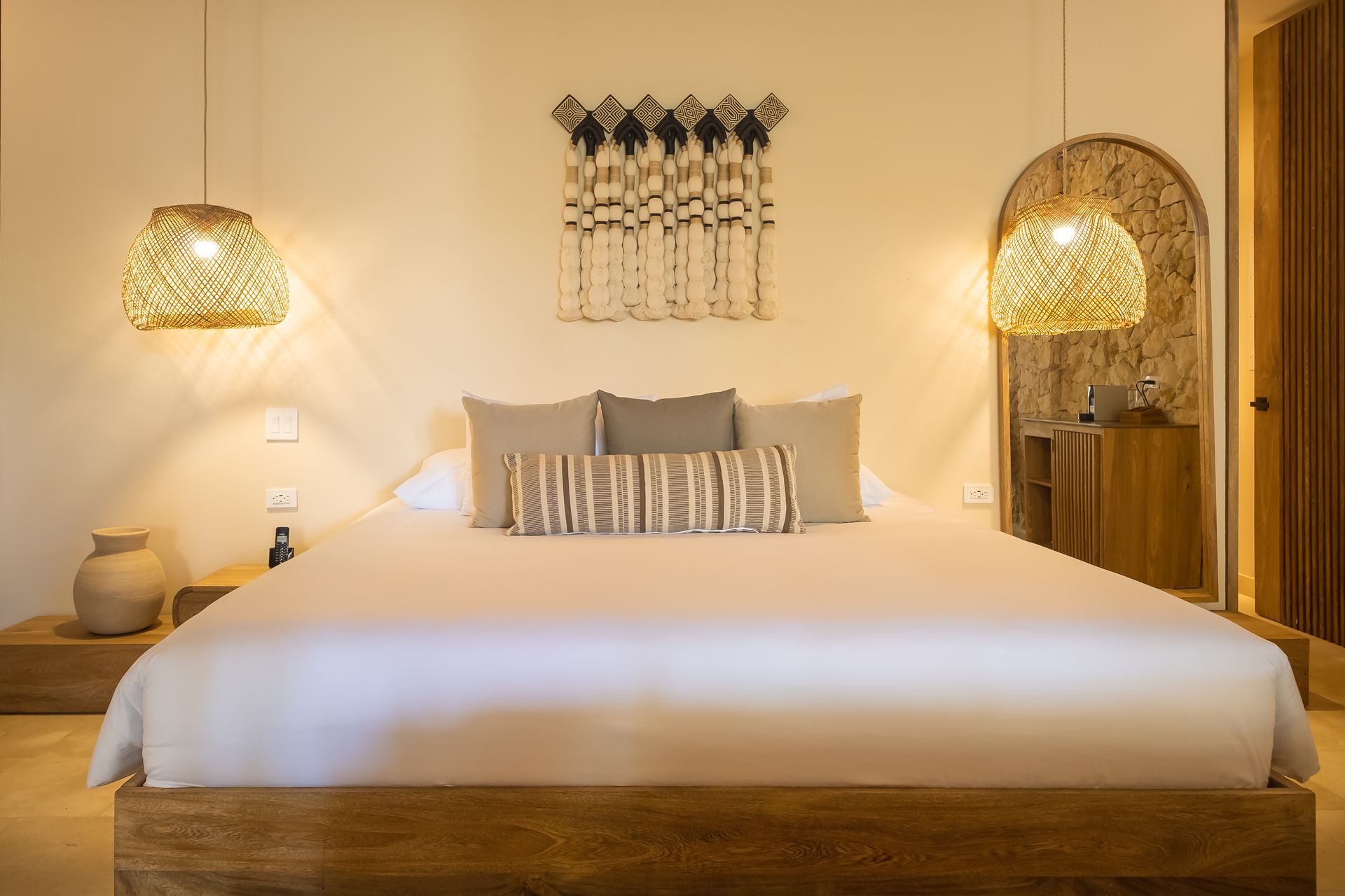 Main bed in the Ameyal Suite at Aimarawa, an oceanfront hotel in San Antero, with soft lighting.
