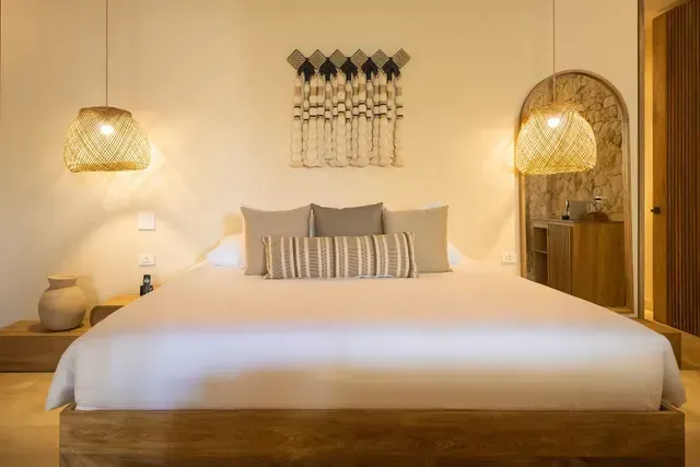 Cama principal en la suite ameyal de Aiamrawa hotel en san antero frente al mar, con iluminación suave y una atmósfera serena